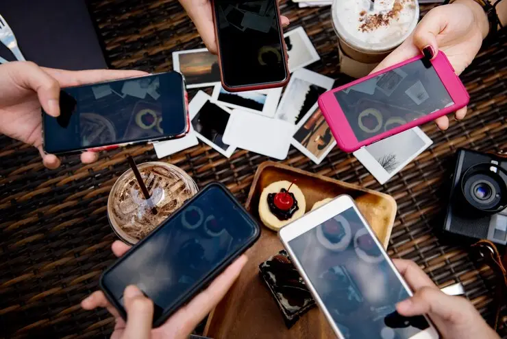 Vários celulares apontando para pratos de comida e fotografias em cima de uma mesa, exemplificando micro-momentos