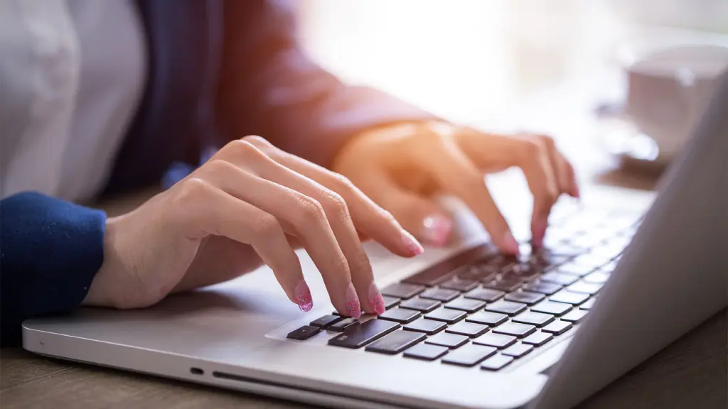 Mão digitando em um notebook, simbolizando o uso da Inteligência Artificial.